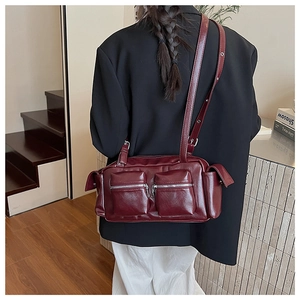 Close-up of a dark red multi-pocket shoulder bag with functional silver zippers
