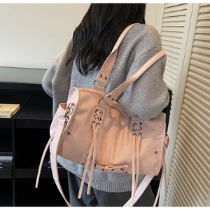 Vue détaillée du sac porté épaule rétro rose poudré avec rivets et cordons latéraux