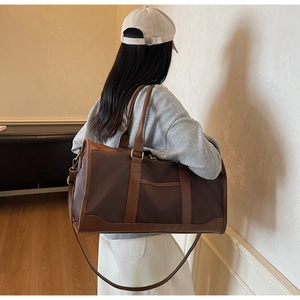 Detail showing high-capacity travel bag with dual handles and metal strap buckles