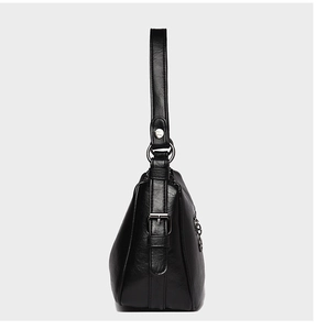 Detail view of black lychee grain leather shoulder bag with silver buckle and wide strap