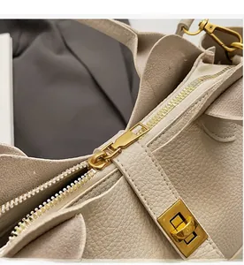 Détail de la fermeture éclair dorée sur un sac seau beige en cuir à grain lychee