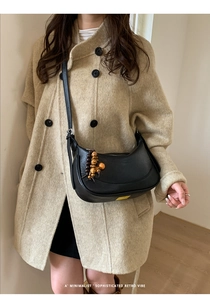 Dettaglio di una borsa a tracolla vintage nera con ciondolo in legno e trama in morbida pelle
