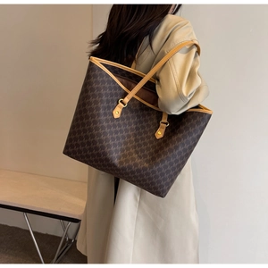 Detail of the large tote bag with geometric M-print and brown leather trim on a model