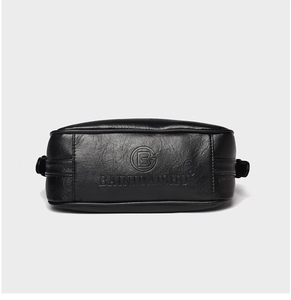 Detailed view of black litchi texture leather with embossed logo on a shoulder bag