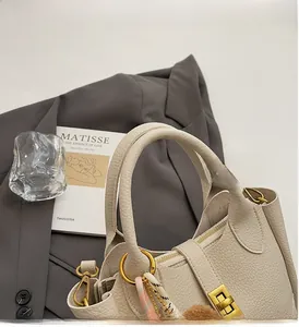 Détail du sac seau en cuir grainé blanc cassé avec ferrures dorées et breloque rose