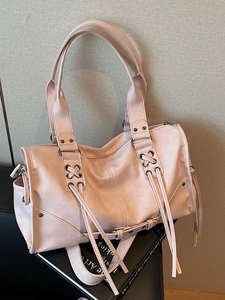 Sac Boston en cuir rose avec pompons décoratifs et détails de laçage sur fond noir