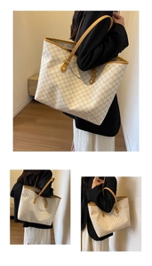 Detail of large tote bag with M-letter monogram pattern and brown leather straps