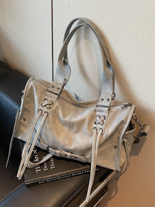 Sac à main rétro gris avec franges et sangles tressées sur un canapé en cuir