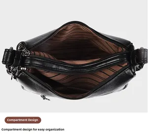 Detailed top view of a black leather bag showing three zipped compartments and striped lining