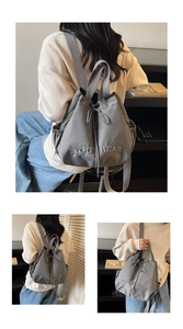 Detail of grey drawstring backpack featuring embroidered letters and side mesh pockets