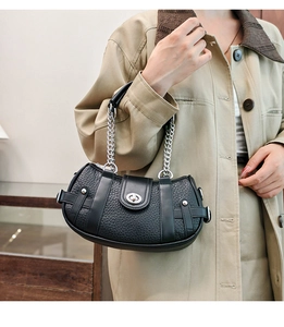 Close-up of black lychee grain leather handbag with silver twist lock and chain strap