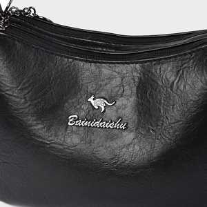 Close-up of black lychee texture leather handbag with silver kangaroo metal logo detail