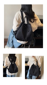 Detail of the black drawstring bucket bag with YOU BEAR embroidery and sturdy straps