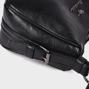 Macro shot of black pebbled leather texture and gunmetal hardware on a handbag