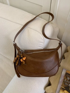 Borsa a spalla vintage in pelle marrone con ciondolo di perline su un divano