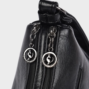 Close-up of black lychee grain leather handbag featuring dual silver kangaroo zips