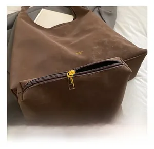 Détail du zip doré et de la texture suédée marron sur cet ensemble de sacs rétro