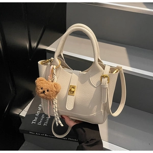 Détail du sac seau crème texturé litchi avec fermoir métallique et breloque ourson