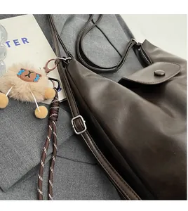 Dettaglio della borsa tote in pelle PU marrone con tracolla regolabile e ciondolo peluche