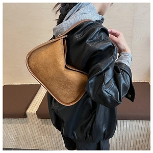 Detail view of the suede stitching and smooth leather trim on a vintage brown shoulder bag