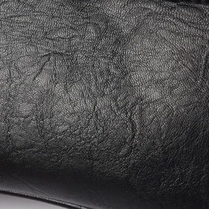 Macro shot of black lychee grain leather texture on a minimalist handbag detail