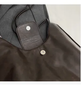 Dettaglio della chiusura magnetica lucida su una borsa tote vintage in pelle marrone