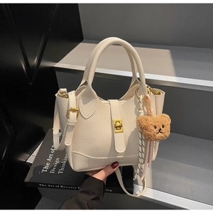 Détail du sac seau en cuir grainé avec fermoir doré et pendentif ourson en peluche