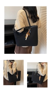 Close-up of minimalist black canvas tote bag featuring colorful wood bead tassel charm