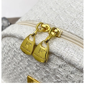 Detail of golden metal zippers with Keddy Bear logo on a white tweed backpack fabric