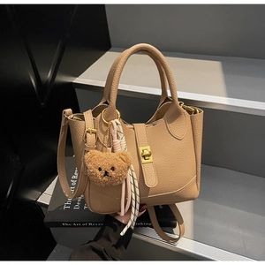 Détail du sac seau en cuir litchi kaki avec boucle métallique et breloque ours