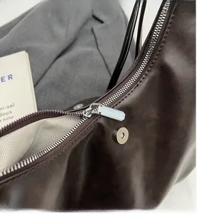 Dettaglio della zip argento e chiusura magnetica sulla borsa marrone con fodera a spina