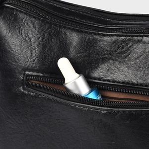 Detailed macro view of black lychee leather exterior pocket with a secure zipper closure