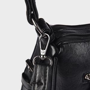 Detail of silver swivel hook and litchi grain texture on a black faux leather bag