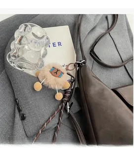Macro di un ciondolo in peluche kaki con gancio in metallo su una borsa di pelle