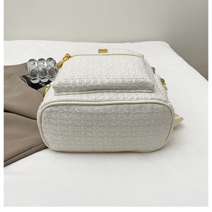 Detail of white tweed backpack with gold hardware in a stylish lifestyle setting