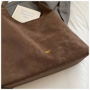 Detail of brown vintage suede tote bag with brand logo in a stylish lifestyle setting