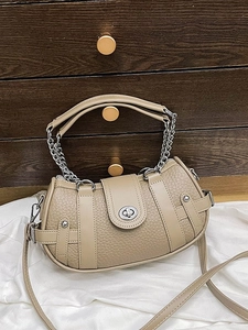 Vintage oatmeal leather handbag with chain strap and metal clasp on a wooden drawer