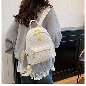 Detail of tweed texture and golden hardware on a stylish cream backpack for women