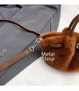 Detail van bruine pluche handtas met geplooide imitatie konijnenbont en metalen gesp