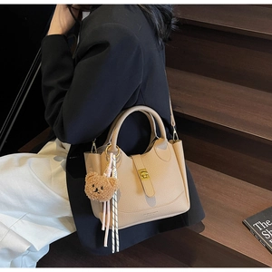 Détail du sac seau en cuir grainé avec fermoir doré et pendentif ourson en peluche