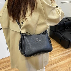 Detail of the black leather texture and silver kangaroo logo on an adjustable crossbody bag