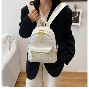 Close-up of white tweed mini backpack with gold logo plate and premium metal zippers