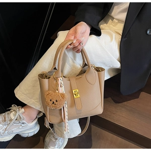 Détail du sac seau en cuir litchi kaki avec fermoir doré tournant et foulard en soie
