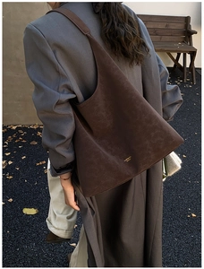 Détail d'un sac cabas en cuir marron vintage avec lettres dorées et bandoulière élégante