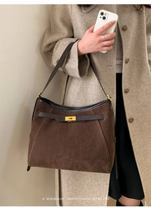 Dettaglio di una borsa tote in pelle scamosciata marrone con chiusura a scatto dorata