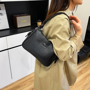Minimalist black leather shoulder bag with kangaroo logo shown in a stylish lifestyle setting