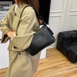 Detail of black pebbled leather handbag featuring a silver metallic kangaroo logo plate