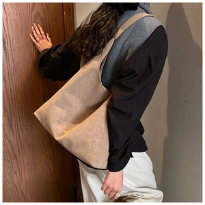 Detailed close-up of light khaki tote bag with textured faux leather and gold logo