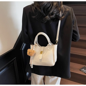 Détail du sac seau blanc à motif litchi avec fermoir doré et breloque ourson