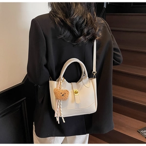 Détail du sac seau en cuir grainé avec boucle dorée et breloque ours en peluche